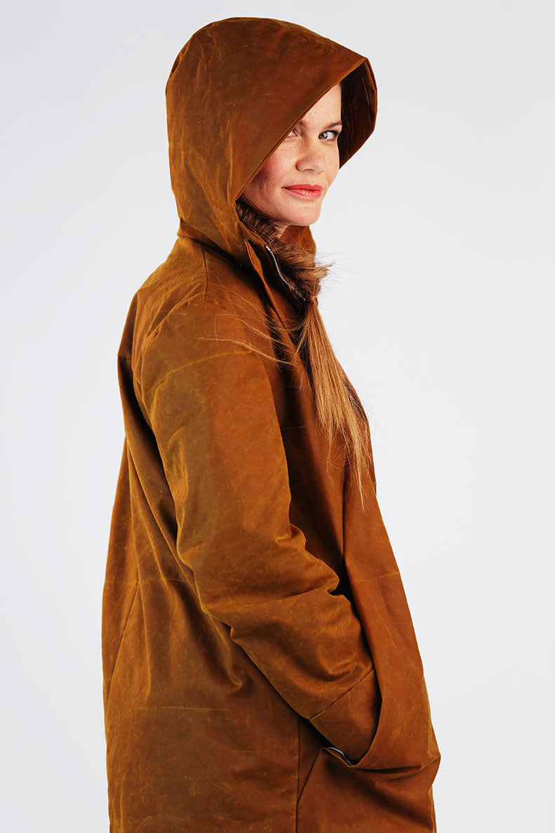 eine Frau kuckt seitlich lächelnd durch die Kapuze ihres selbst genähten Parkas in Richtung Kamera