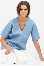 eine Frau sitzt mit ihrem Blauem Shirt vor einem weißen Hintergrund