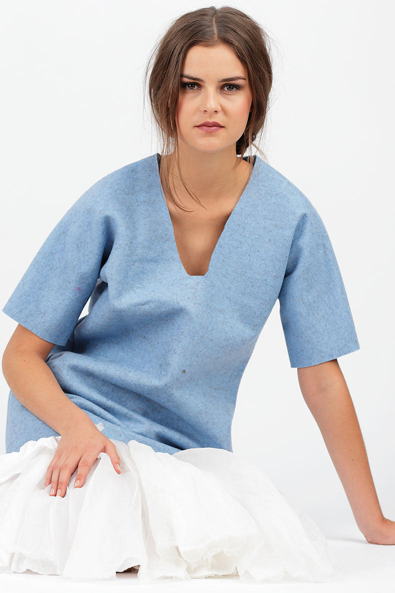 eine Frau sitzt mit ihrem Blauem Shirt vor einem weißen Hintergrund