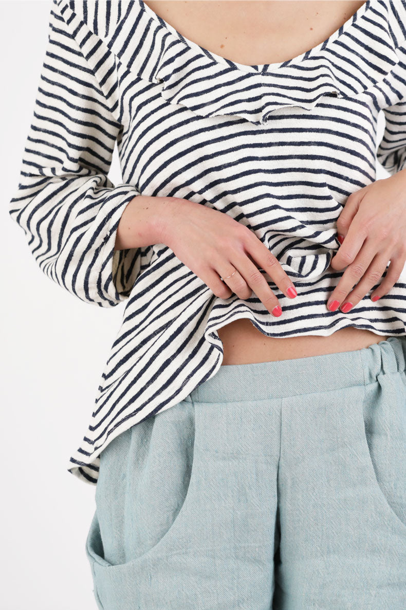 eine Frau, die ein gestreiftes Oberteil und eine blaue Hose trägt.
