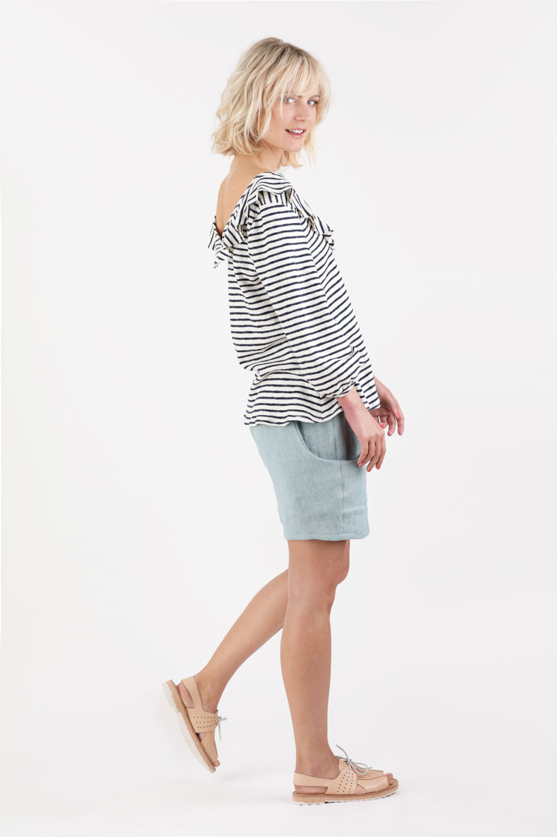 eine Frau, die ein gestreiftes Oberteil und blaue Shorts trägt.