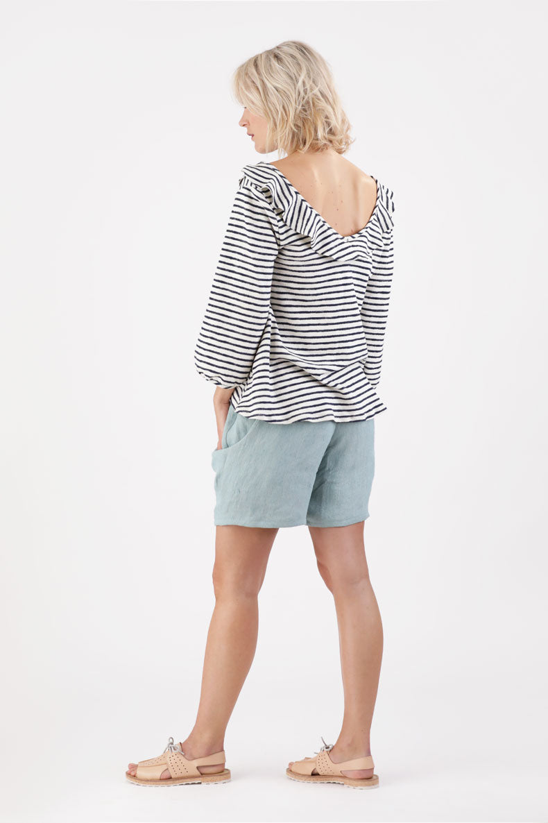 die Rückansicht einer Frau, die ein gestreiftes Oberteil und Shorts trägt.