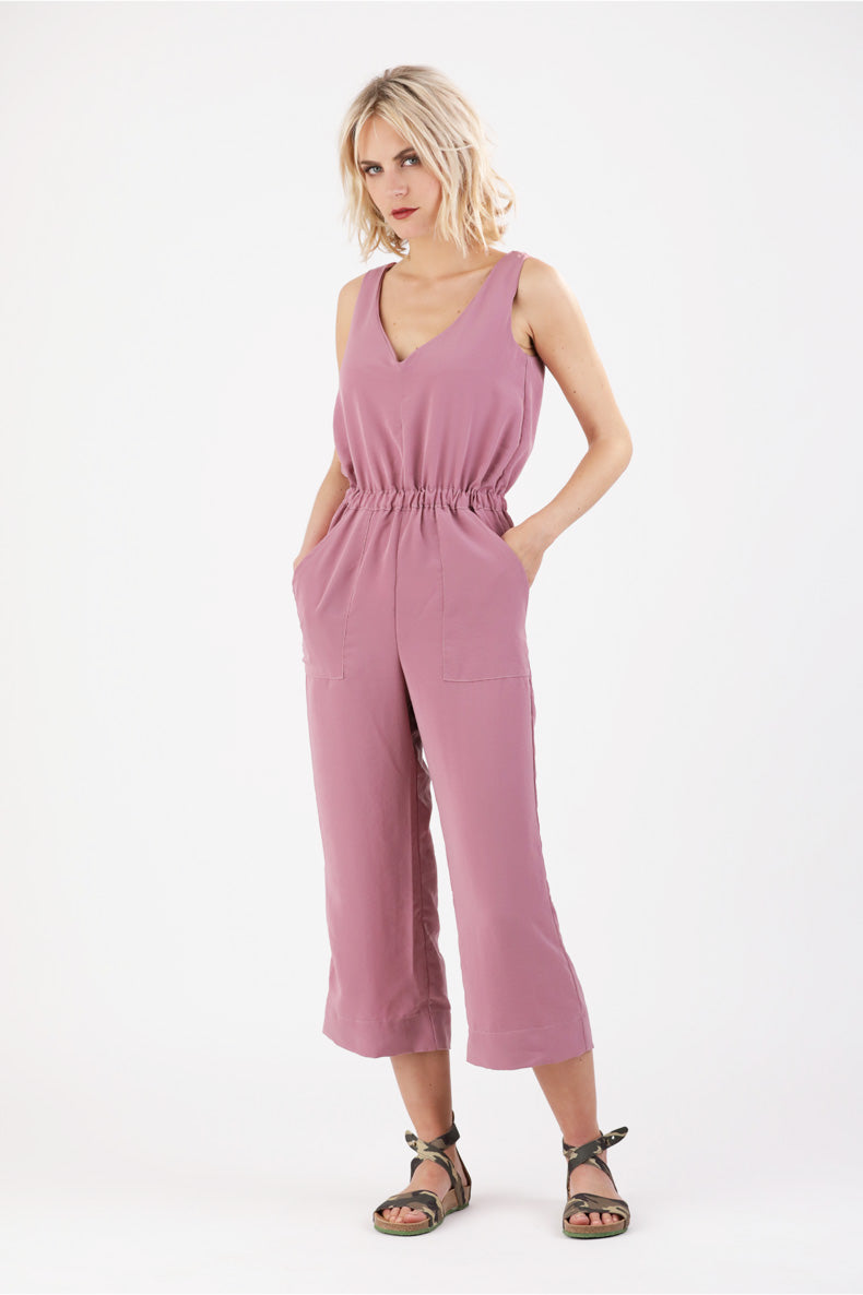 eine Frau welche die Hände in den Taschen ihres Jumpsuits versteckt