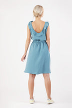 Rückensicht einer Frau die ein blaues Kleid mit Rüschen trägt