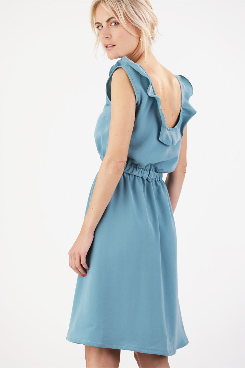 die Rückansicht einer Frau, die ein blaues Kleid mit Rüschen trägt.