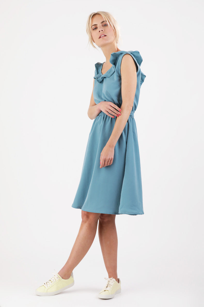 eine Frau, die ein blaues Kleid mit Rüschen trägt.