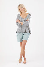 Mit verschränkten Armen schaut eine Frau welche ein Gestreiftes Shirt trägt in die Kamera