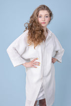 ein Fröhlich in die Kamera sehendes Mädchen welches ein weißes Kleid trägt streckt ihre Ellenbögen aus