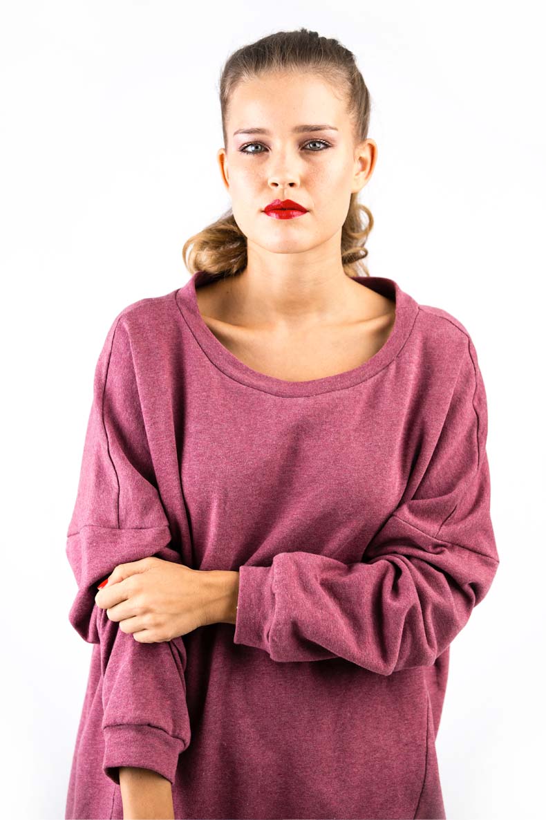 vor einer weißen Wand steht eine Frau mit rotem Lippenstift und einem selbst genähtem Shirt mit rundem Ausschnitt