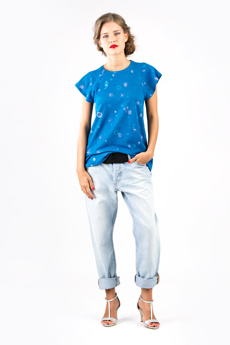 eine Frau mit blauem Shirt posiert vor einer weißen Wand