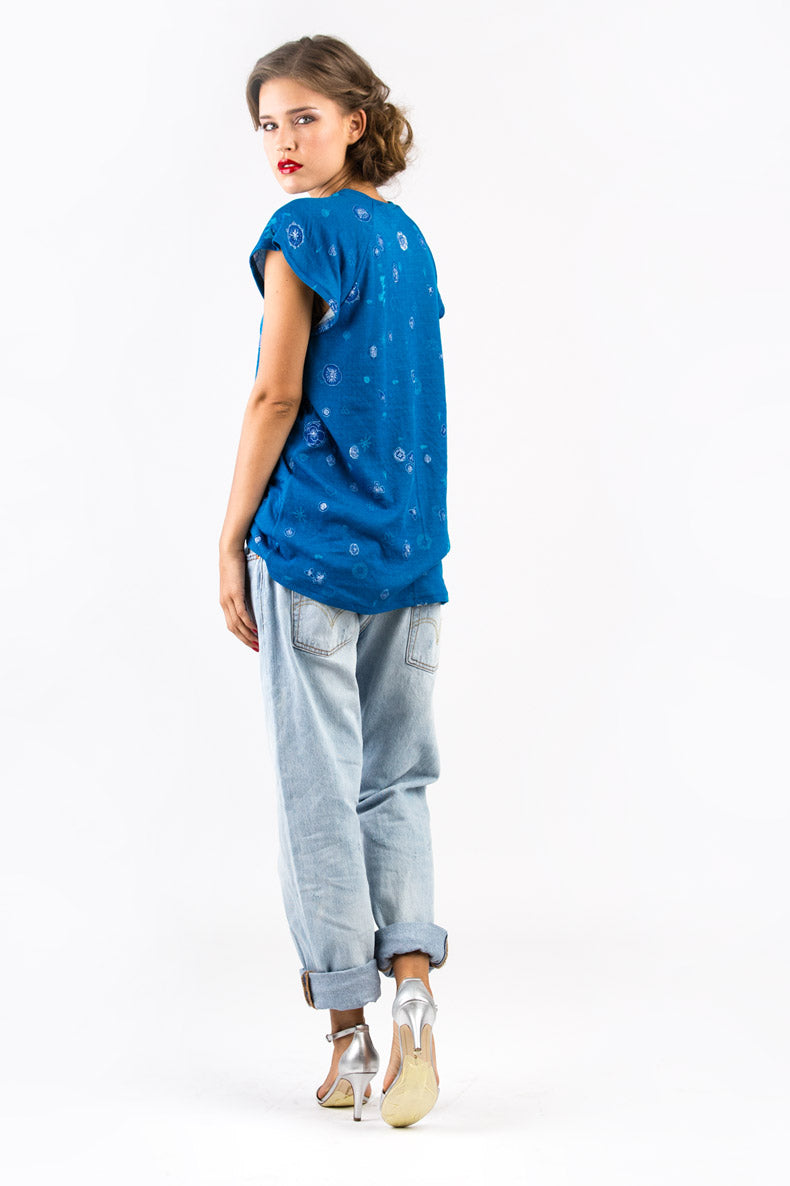 vor einer weißen Wand steht eine Frau mit Stöckelschuhen welche ein blaues Shirt trägt