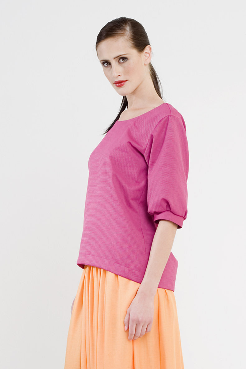 eine Frau mit zaghaften lächeln trägt ihr aus einem Schnittmuster selbst genähtes pinkes Shirt