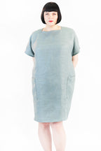 Eine Frau mit einem Grauem Kastenkleid schaut frontal in die Kamera