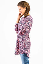 eine Frau mit langen Haaren steht schräg zur Kamera und trägt eine schön gemusterte Tunika