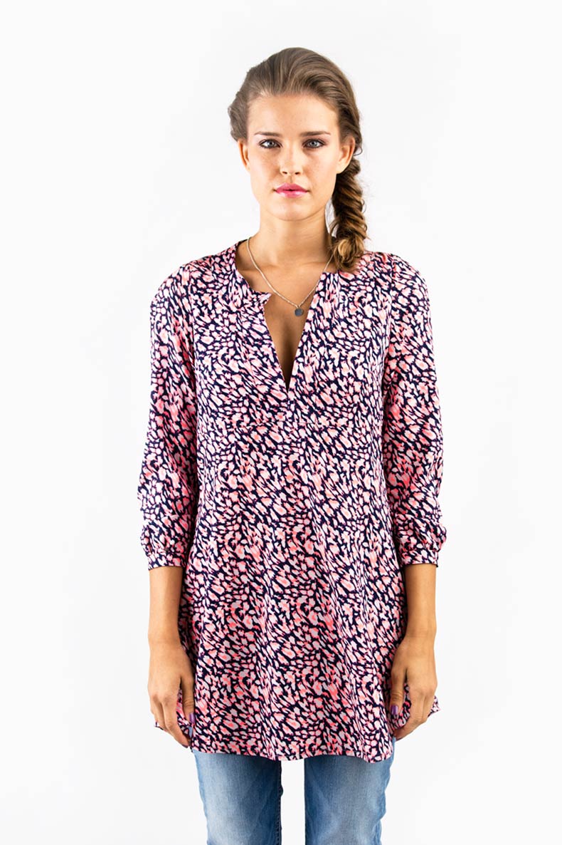 eine Frau trägt eine Tunika mit rosafarbene Leopardenmuster und eine Jeans