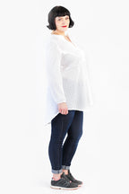 schräg zur Kamera steht eine Frau welche eine mittlere Tunika trägt