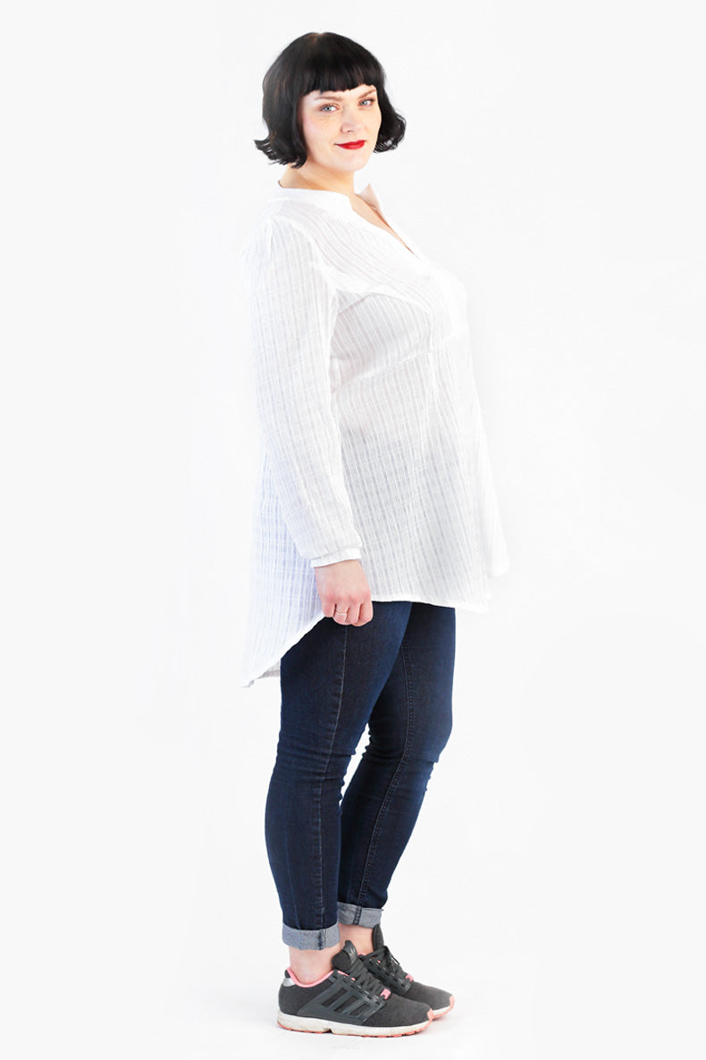 schräg zur Kamera steht eine Frau welche eine mittlere Tunika trägt