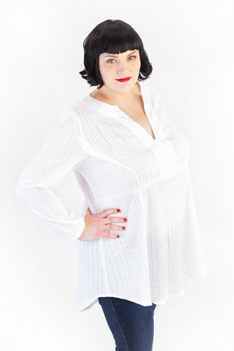 mit ausgestreckten Ellenbogen präsentiert eine Frau ihre selbst genähte Tunika